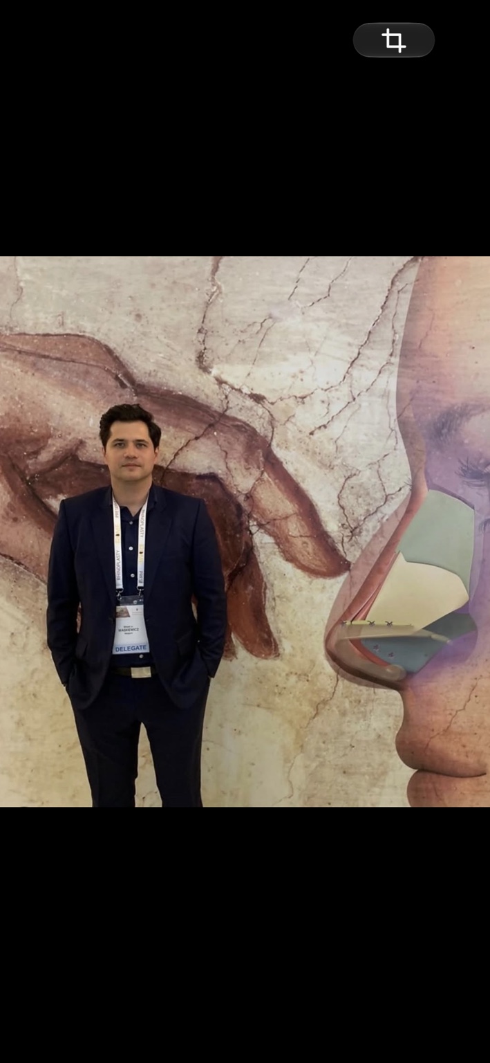 Dr Witold Waskiewicz Jr devant un panneau consacré à la rhinoplastie lors d’un congrès